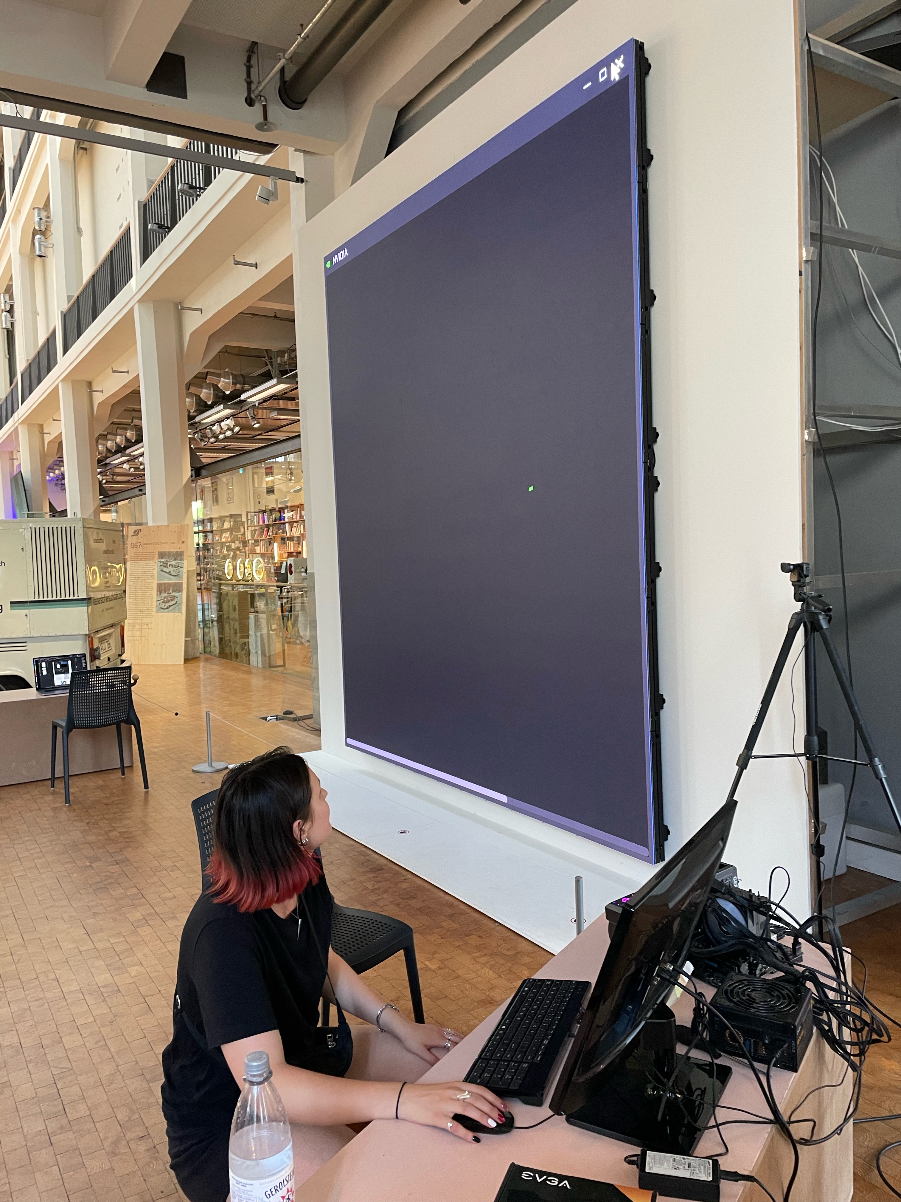 Katharina hockt auf dem Fußboden des ZKM vor einer riesigen LED Wand. Vor ihr ist ein Bildschirm und viel Technik aufgebaut.