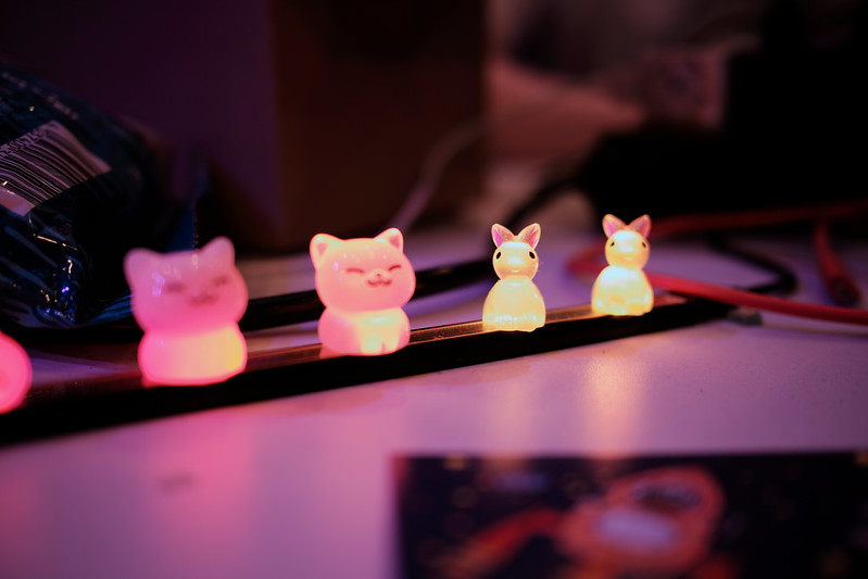 Zwei kleine katzen Figuren sitzen neben zwei kleinen hasen Figuren auf einem LED Streifen.