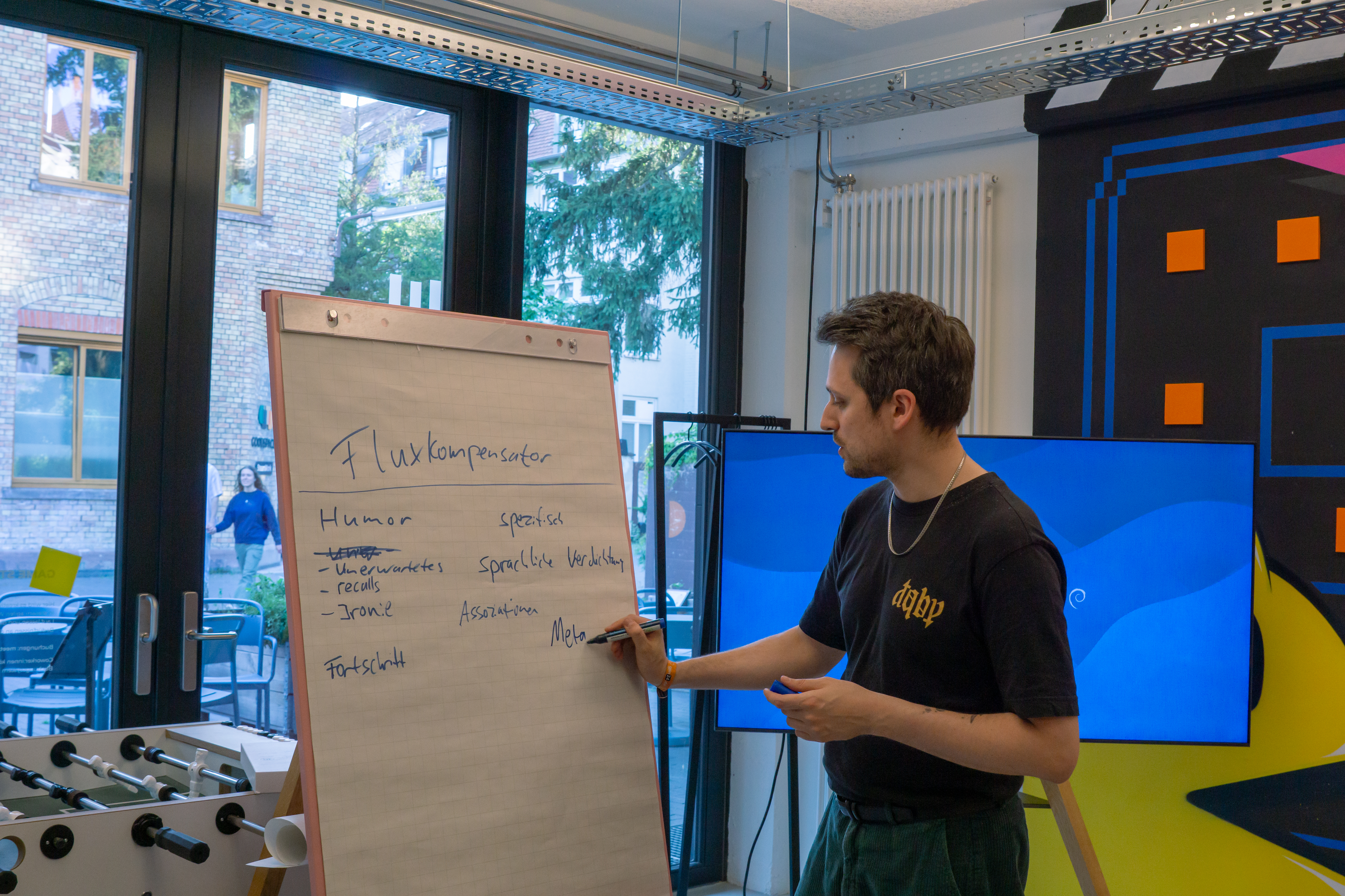 Fabian steht vor einem Flipchart und schreibt einzelne Wörter mit einem Edding auf Papier.