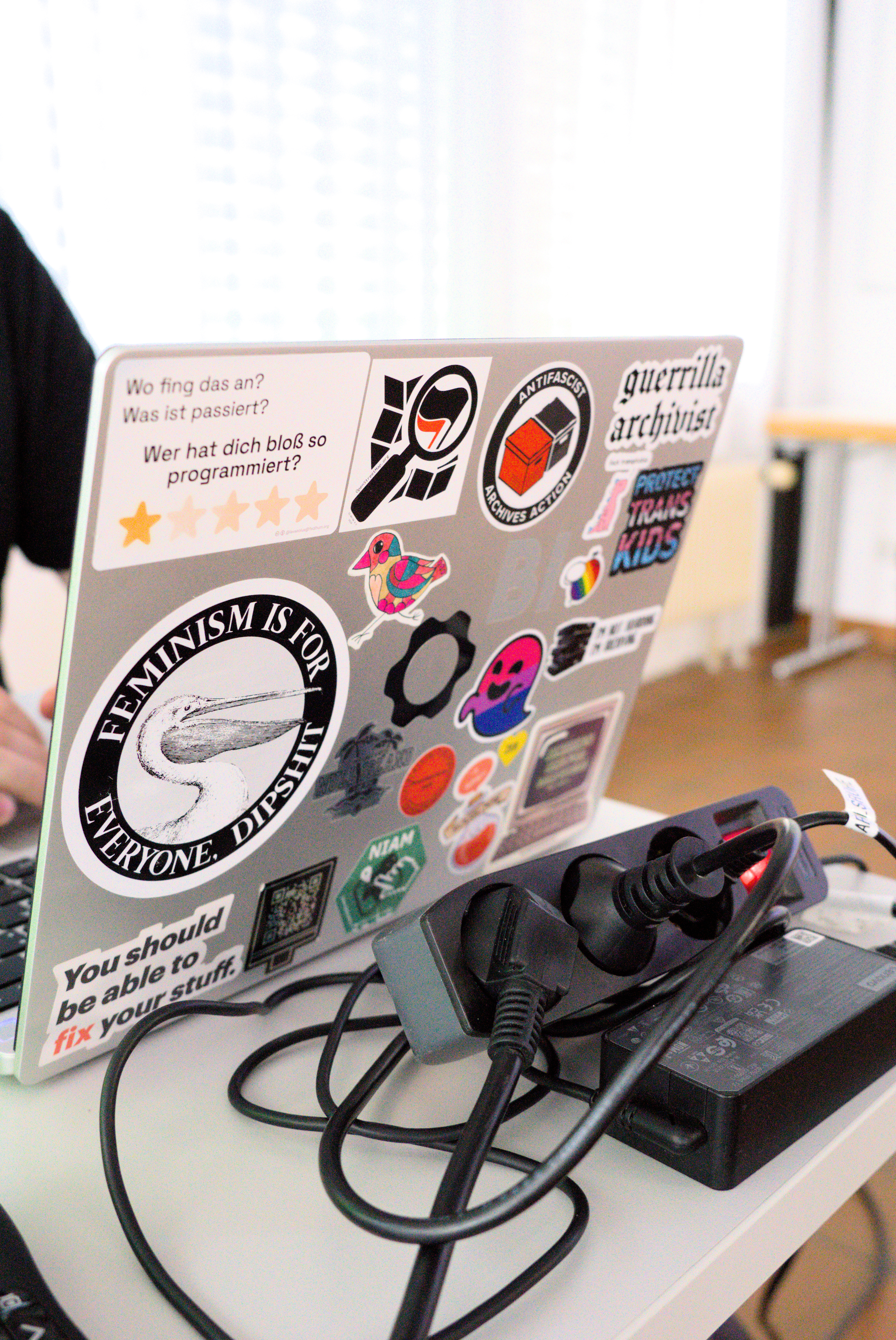 Ein Laptop der vollgeklebt mit bunten Stickern ist. Zum Beispiel: 'Feminismus ist für jeden', 'Alle Sachen sollten reparierbar sein', 'Beschützt trans Kinder'