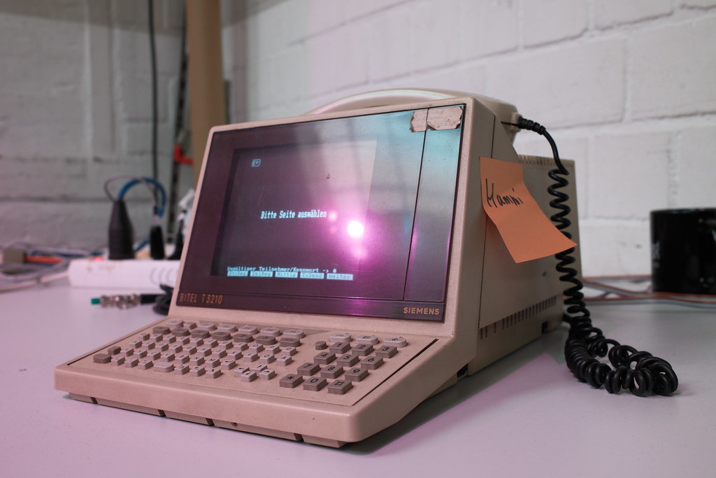 Ein Retro Computer auf einem Tisch mit angeschlossenem Festnetz-Telefon.